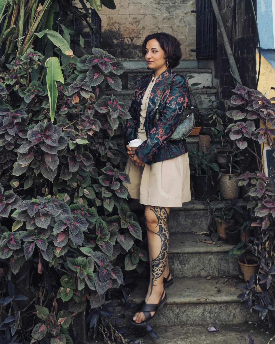 Woman standing on steps surrounded by plants in an outdoor setting